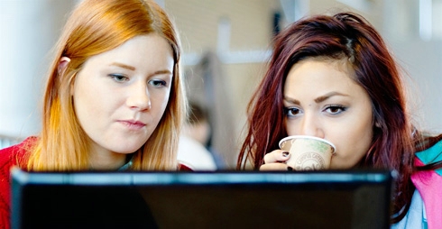 Två tjejer tittar på en dataskärm.