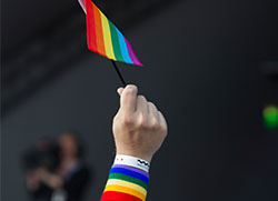 Bild på en hand som håller i en regnbågsflagga. Foto: Mostphots